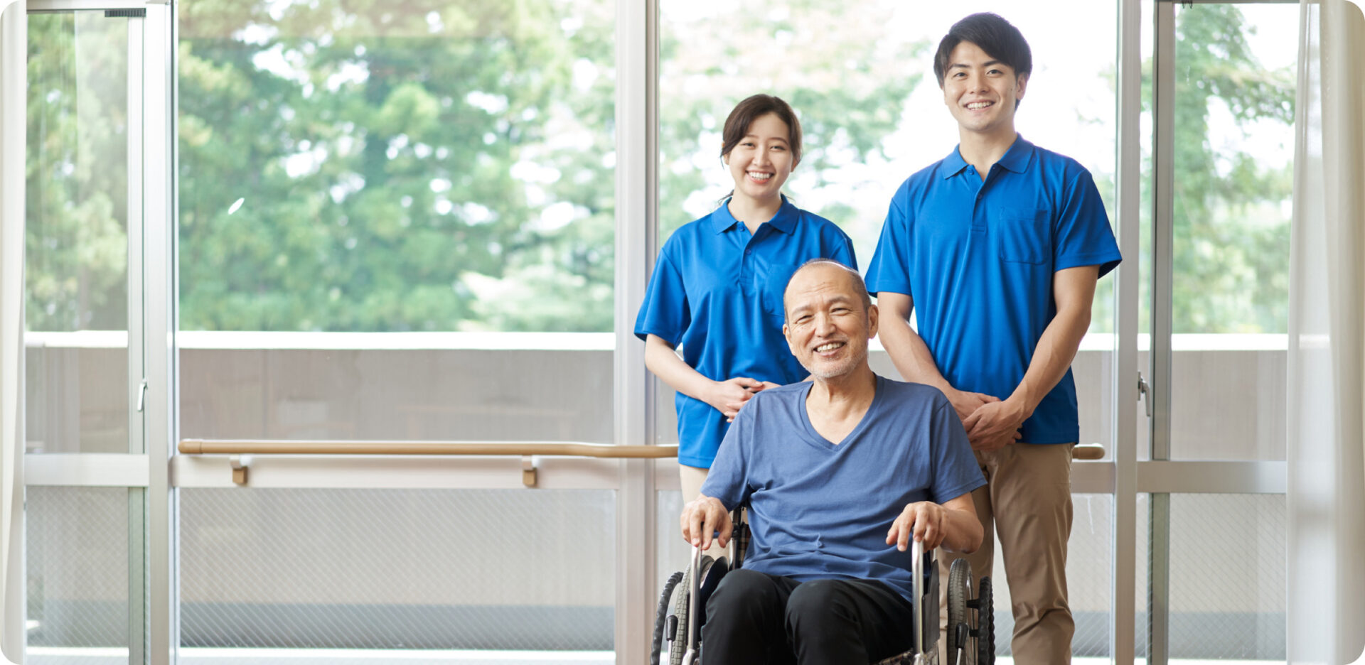 就労継続支援 スタッフ募集 車椅子に座った男性と二人の作業員が笑顔で並んでいる様子