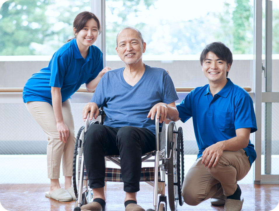 福祉業界 キャリアアップ 車椅子に座った男性と二人の作業員が笑顔で並んでいる様子